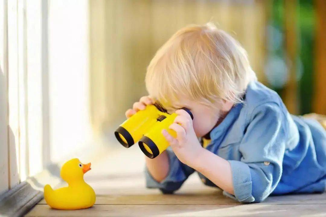 好奇心旺盛的孩子用望远镜观察小黄鸭